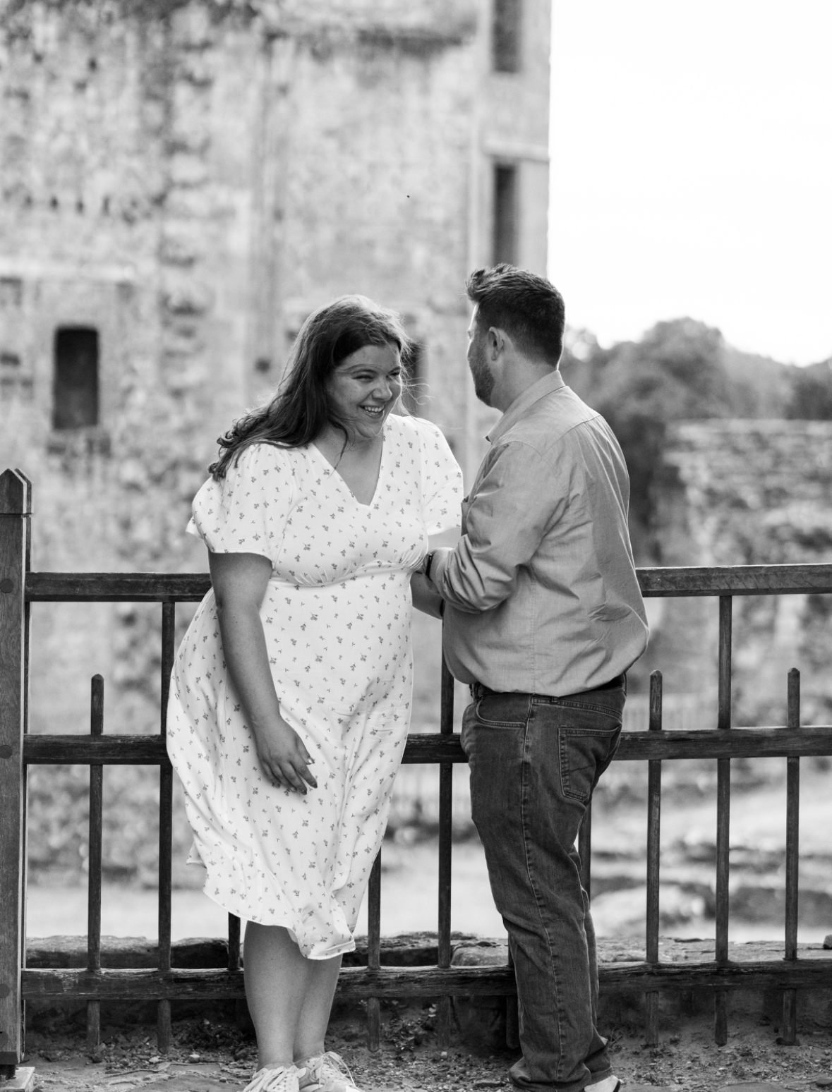 Curvy girl holding onto her husband in a black and white photo